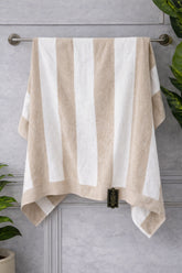 Beige and white striped towel hanging on a towel rack against a gray wall.