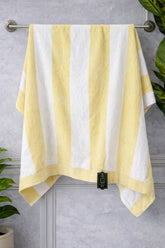 Yellow and white striped towel hanging on a rack with a gray wall background