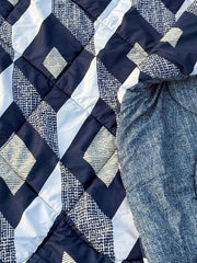 Close-up of a quilt with blue and white geometric pattern and a piece of fabric.