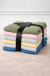 Stack of folded towels in various colors tied with a black ribbon on a light background