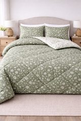 Green floral quilt set on a bed with matching pillows in a bedroom setting.