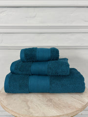 Set of three blue towels on a wooden stand with a white background
