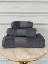 Stack of gray towels on a wooden table with a white wall background