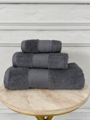 Stack of gray towels on a wooden table with a white wall background
