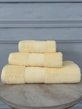 Stack of cream towels on a wooden surface with a gray background