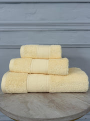 Stack of cream towels on a wooden surface with a gray background