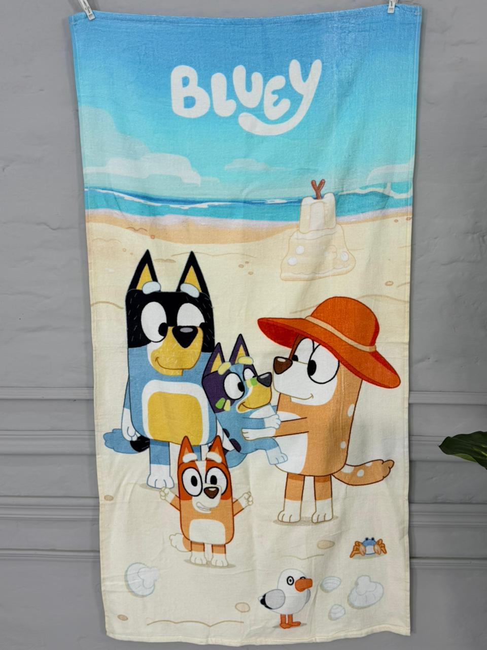 Towel with cartoon characters and 'Bluey' branding on a beach scene.