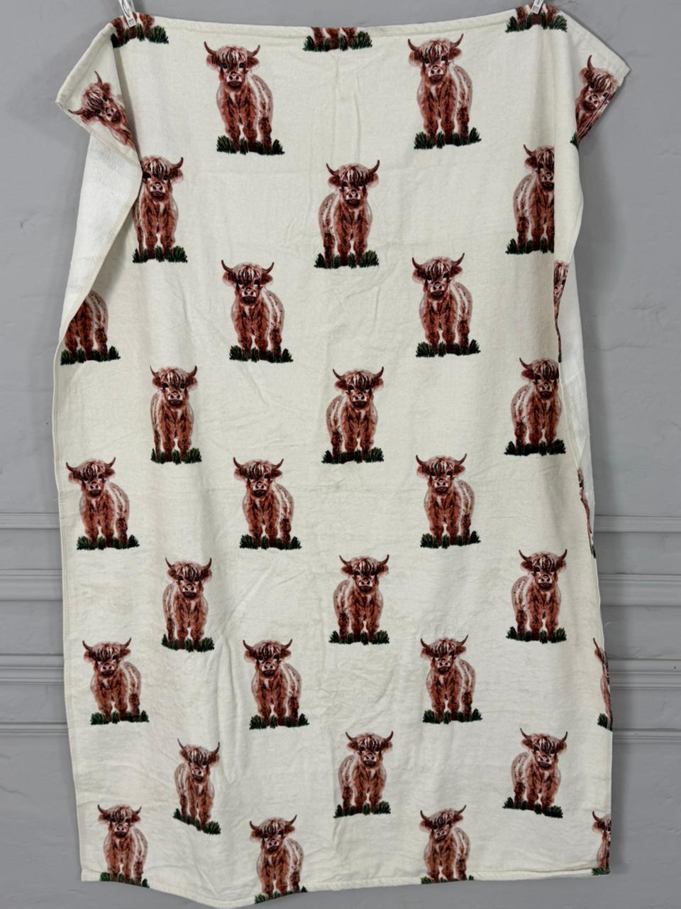 White towel with brown cow pattern draped over a gray surface