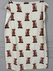 White towel with brown cow pattern draped over a gray surface