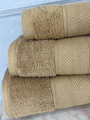 Three beige towels stacked on a white surface with a light blue background