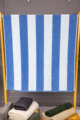 Blue and white striped towel on a wooden rack with folded clothes below.