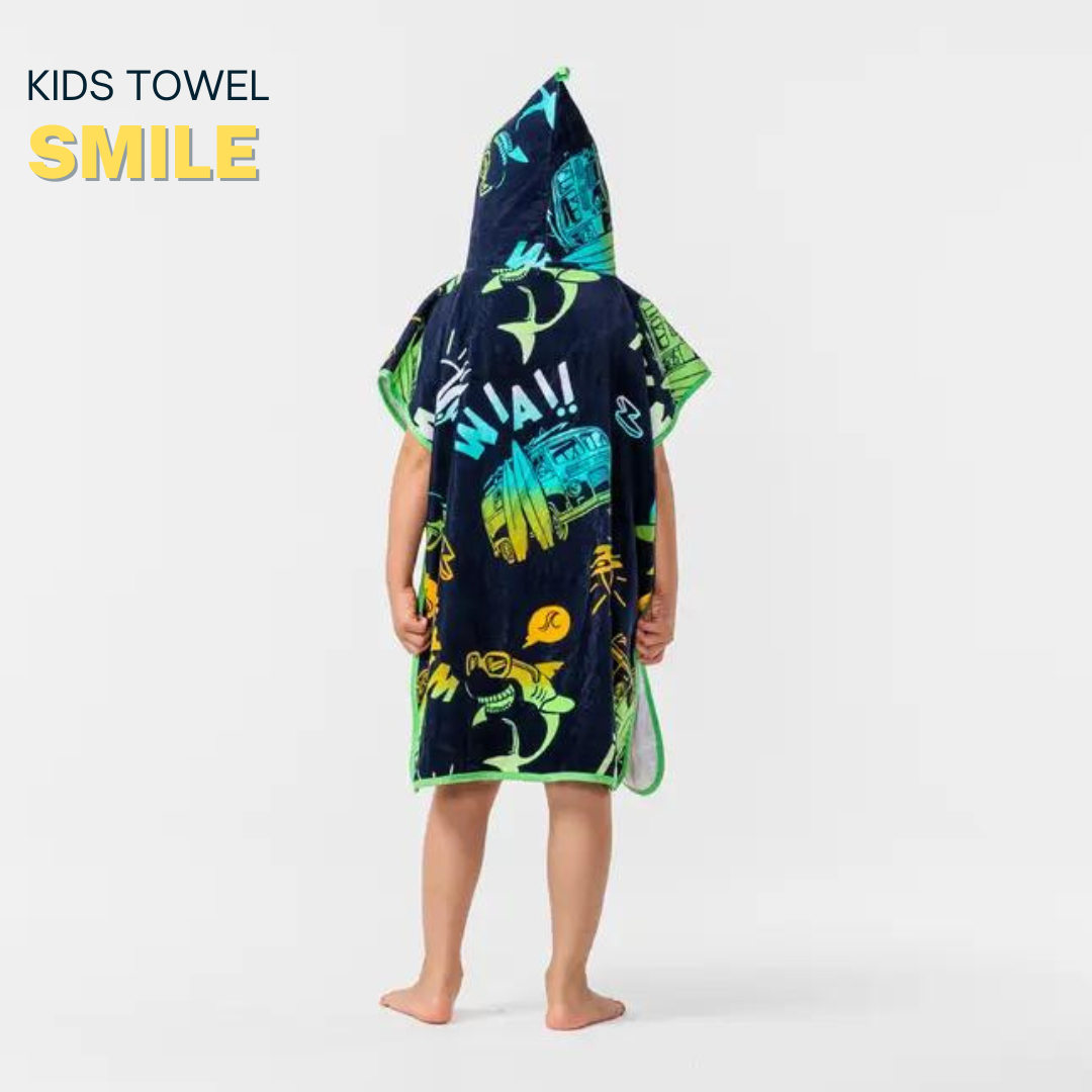 Child wearing a dark blue poncho with colorful dinosaur prints in a bright room.