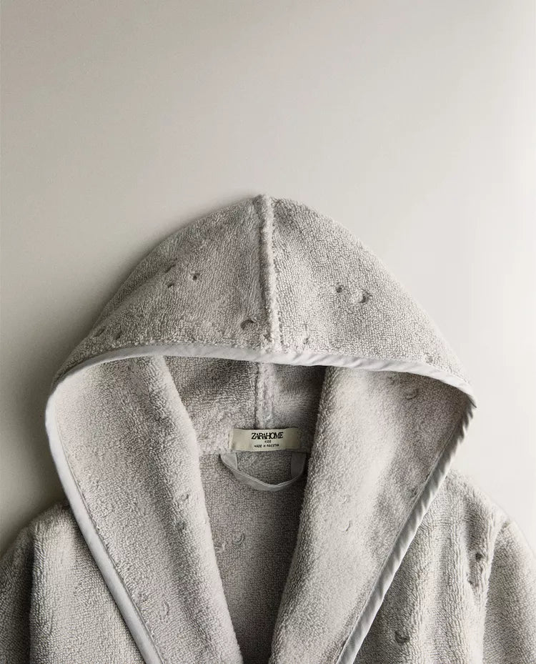 Child wearing a gray hooded robe on a white background
