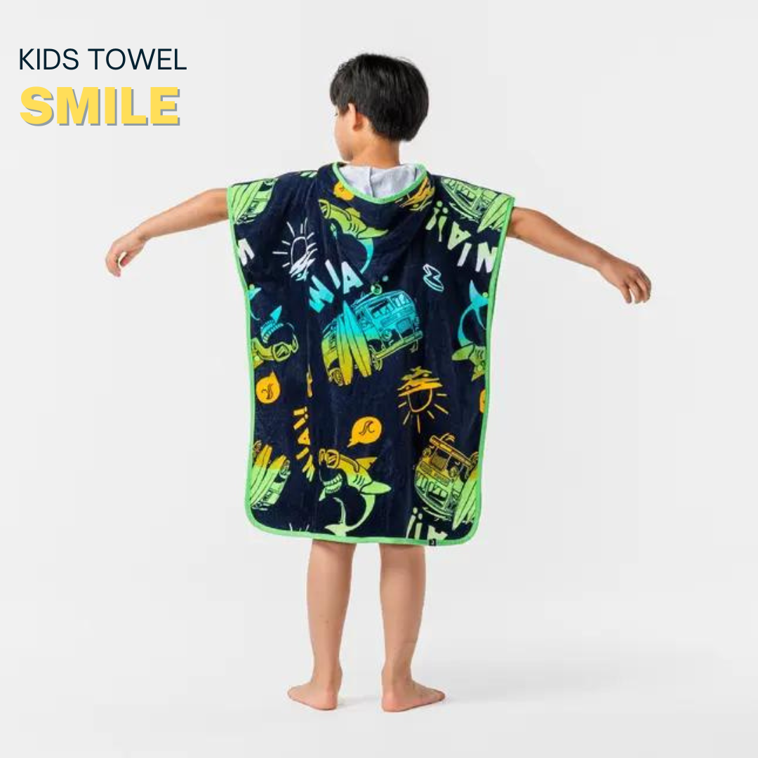 Child wearing a dark blue poncho with colorful dinosaur prints in a bright room.