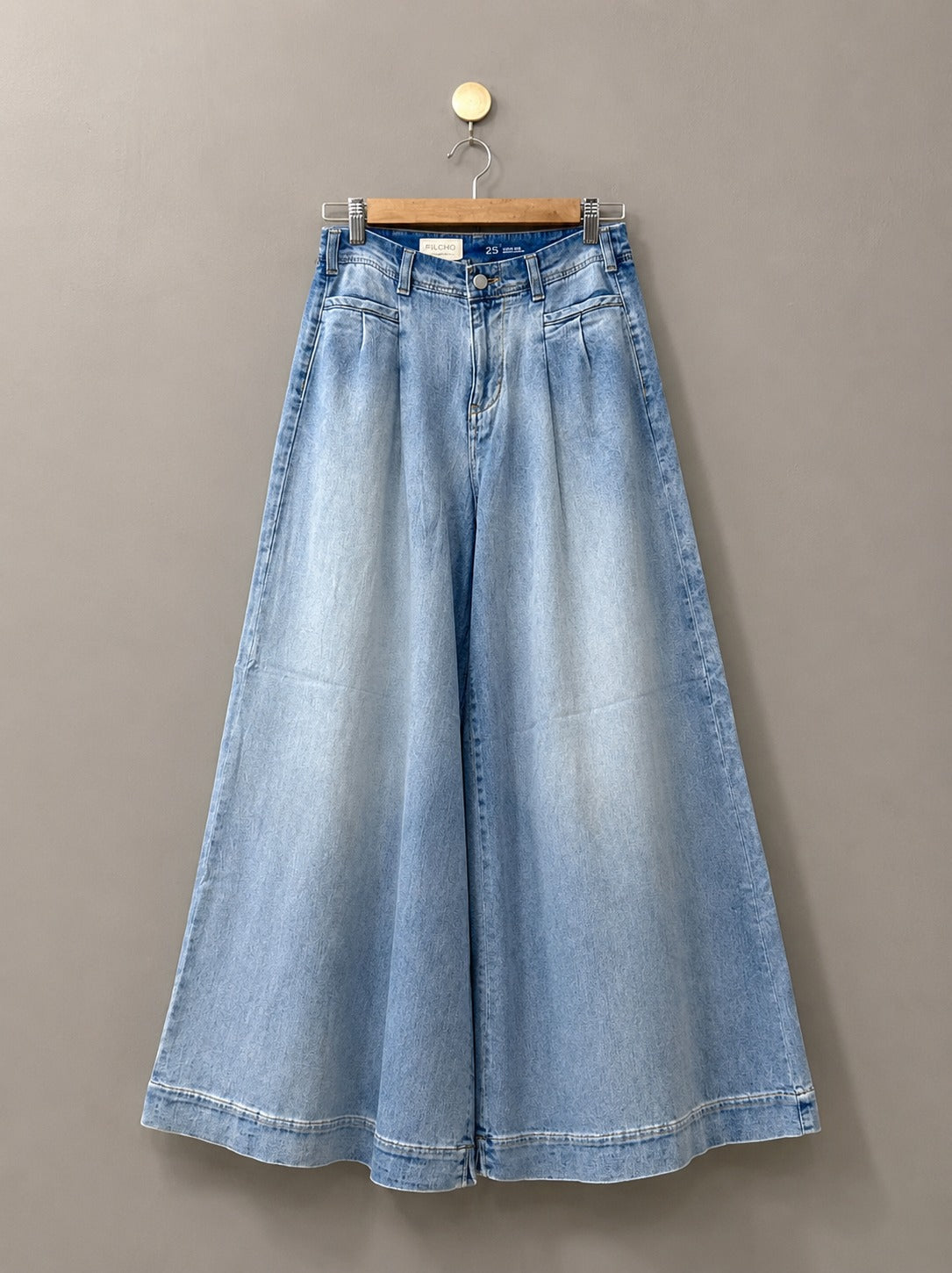 Blue denim skirt on a hanger against a gray background