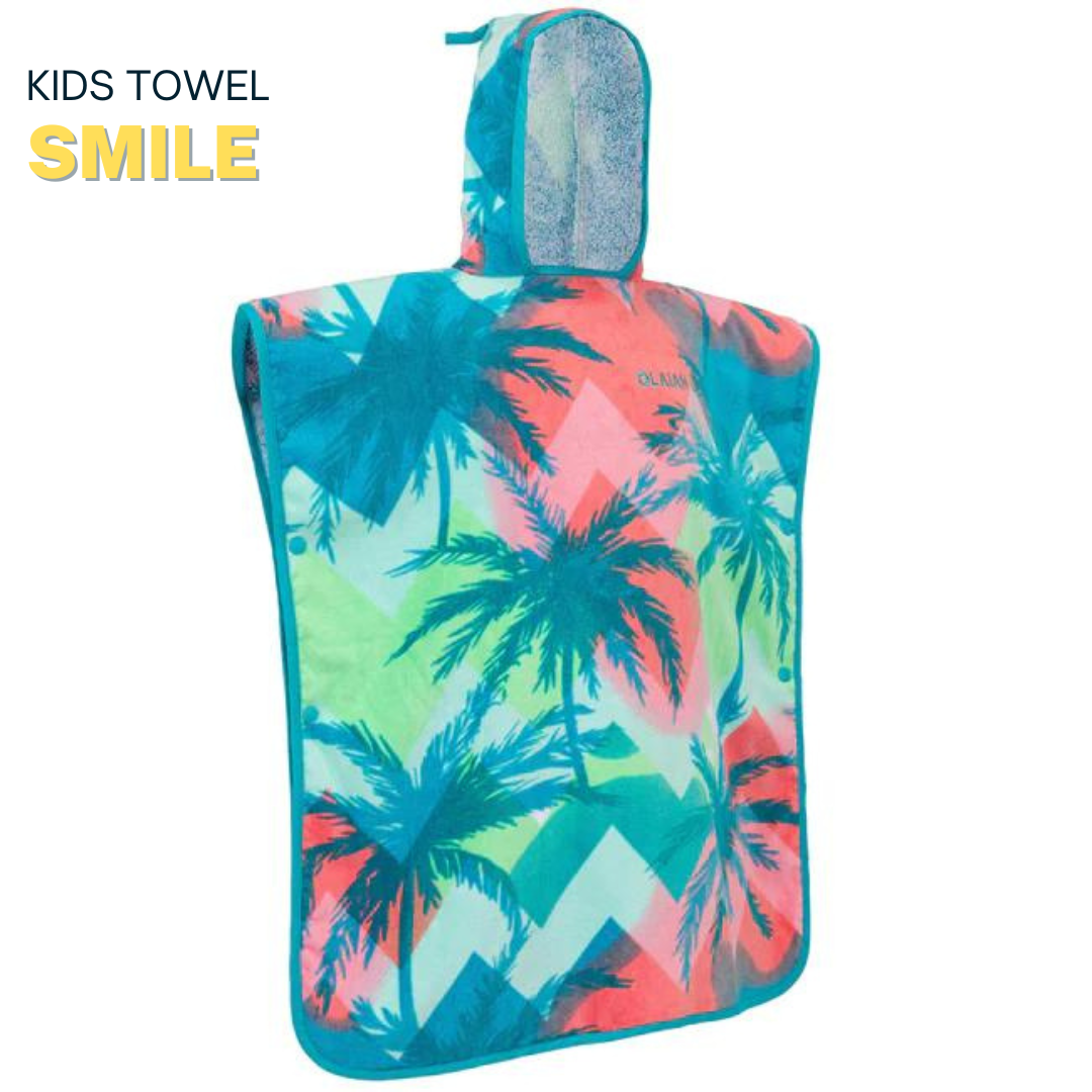 Child wearing a colorful hooded towel with palm tree and sailboat design, standing on a white platform.