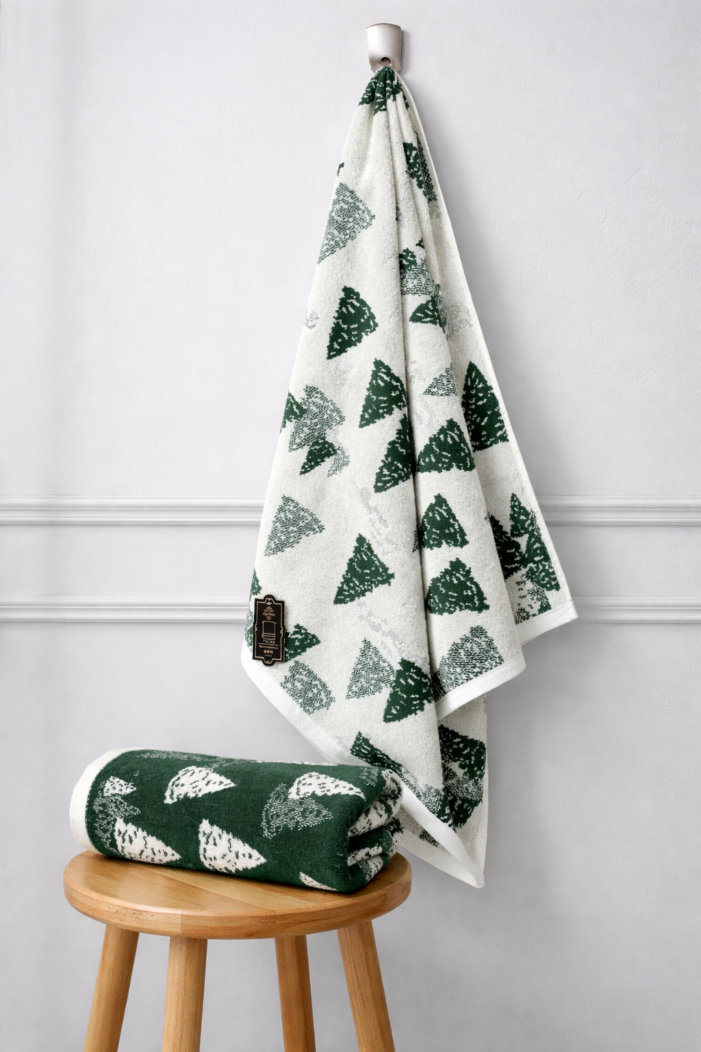 Green and white patterned towel hanging on a hook against a light gray wall.