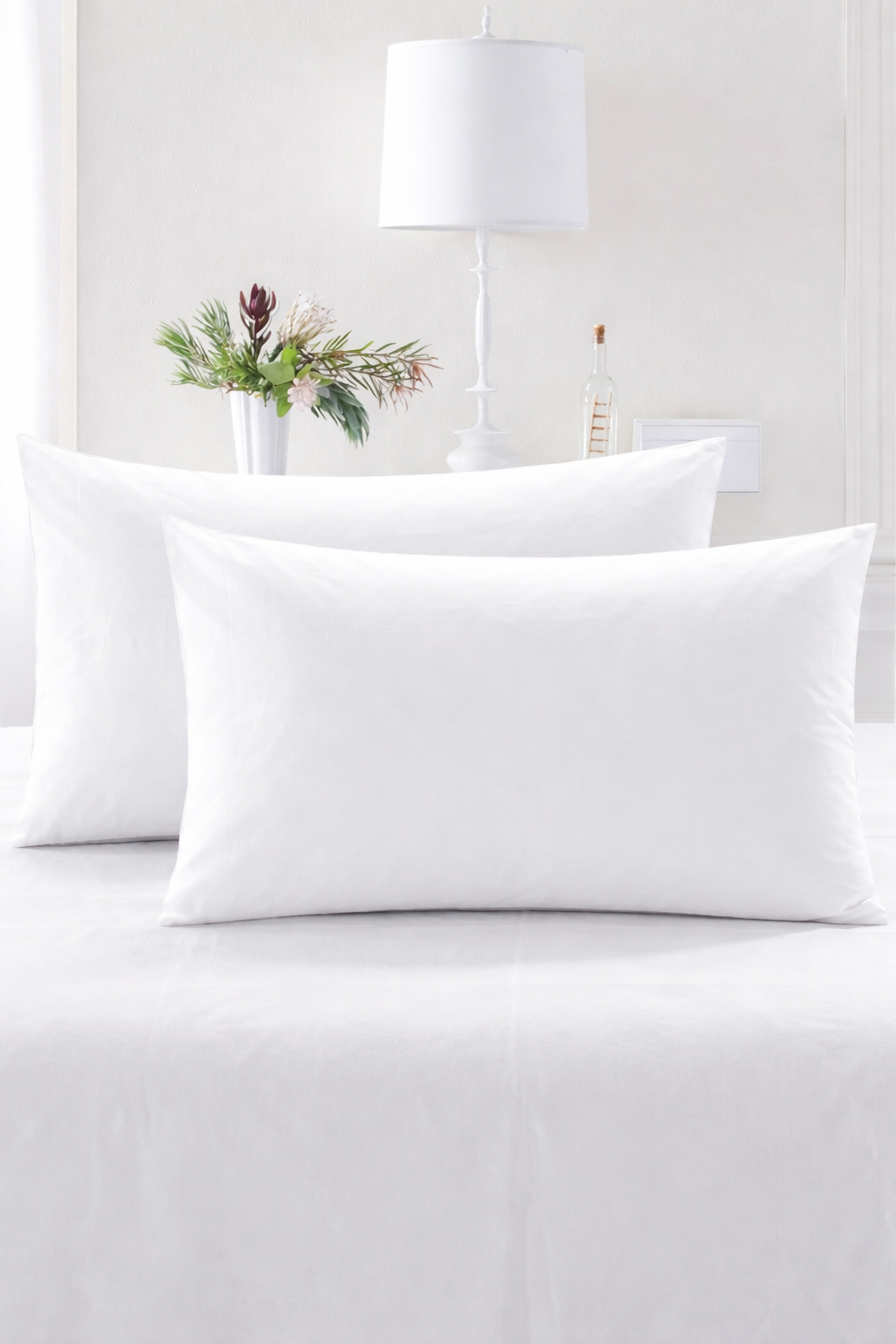 Two white pillows on a bed with a neutral background