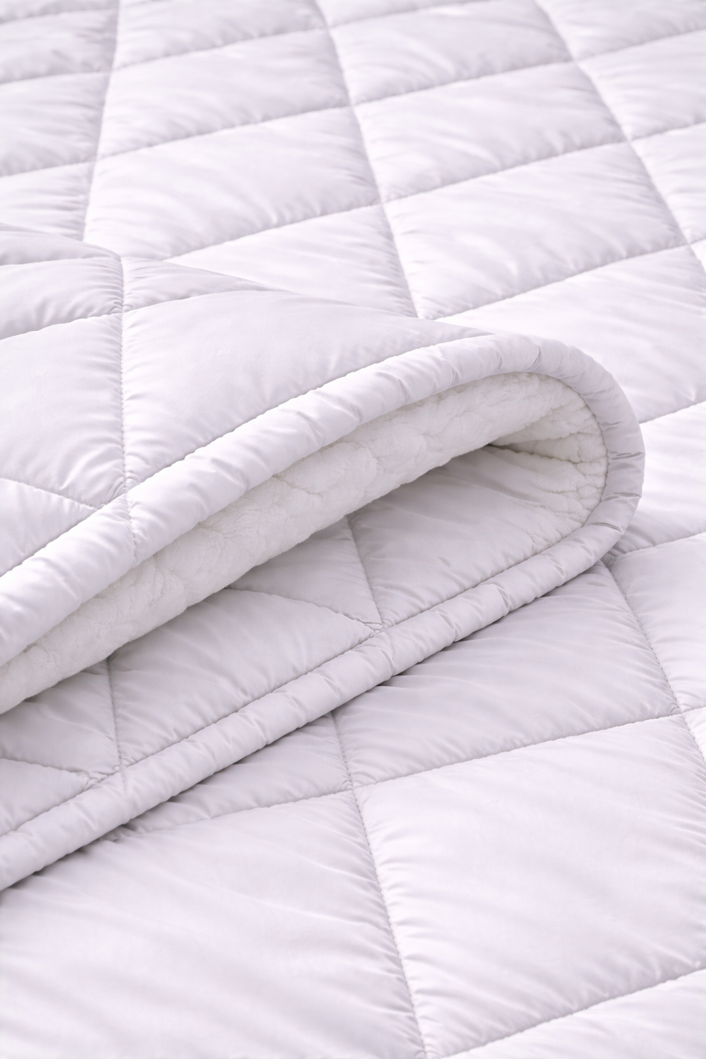 Close-up of a quilted white blanket with a soft texture.
