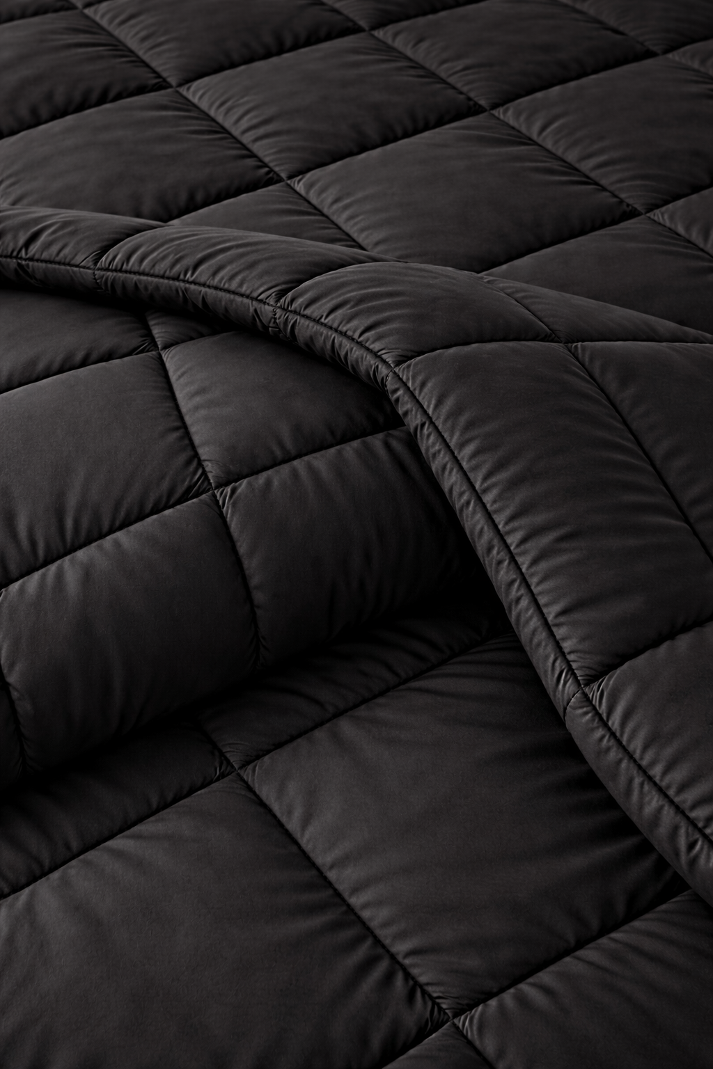 Close-up of a black quilted comforter with diamond pattern