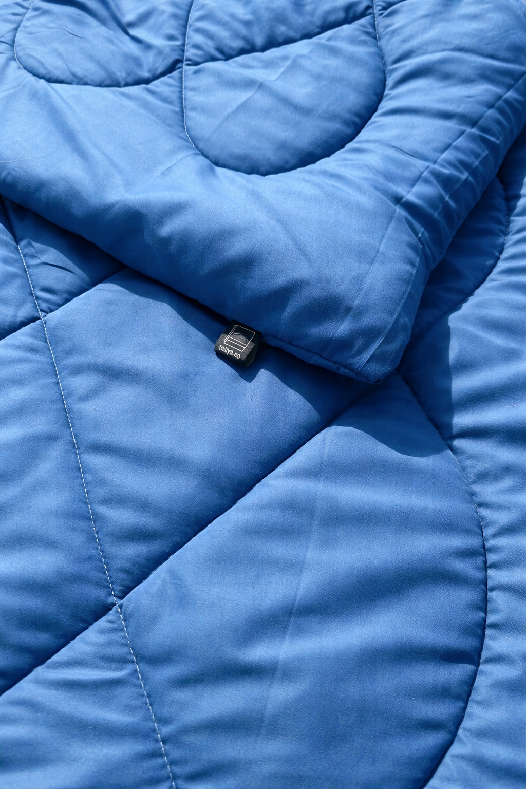 Close-up of a blue quilted jacket with a brand logo.