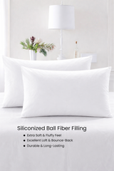 White pillows on a bed with decorative elements in the background, featuring text about siliconized ball fiber filling.