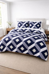 Navy and white geometric patterned comforter set on a bed in a bright bedroom.