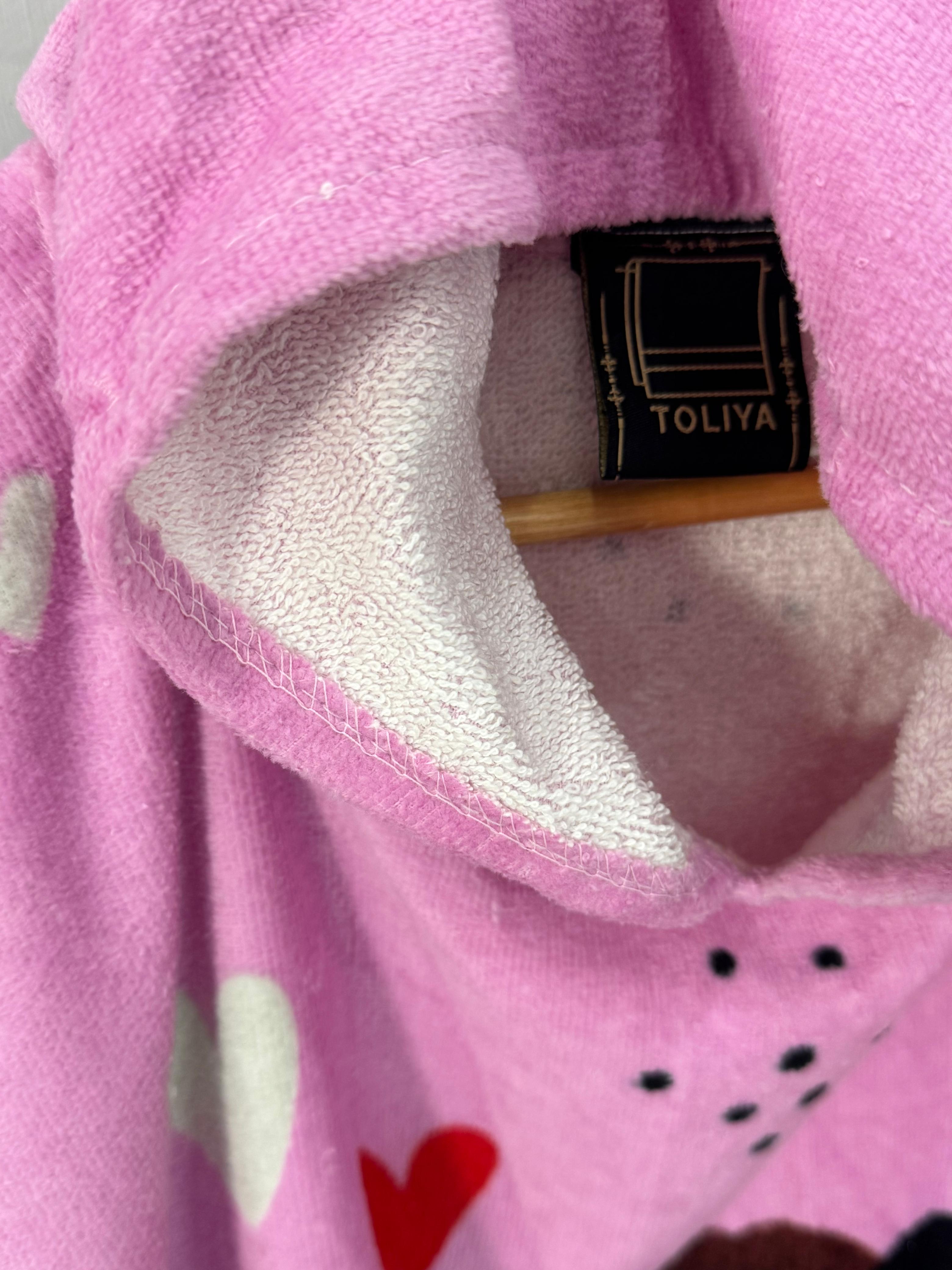 Close-up of a pink fleece blanket with heart patterns and a TOLIYA label.