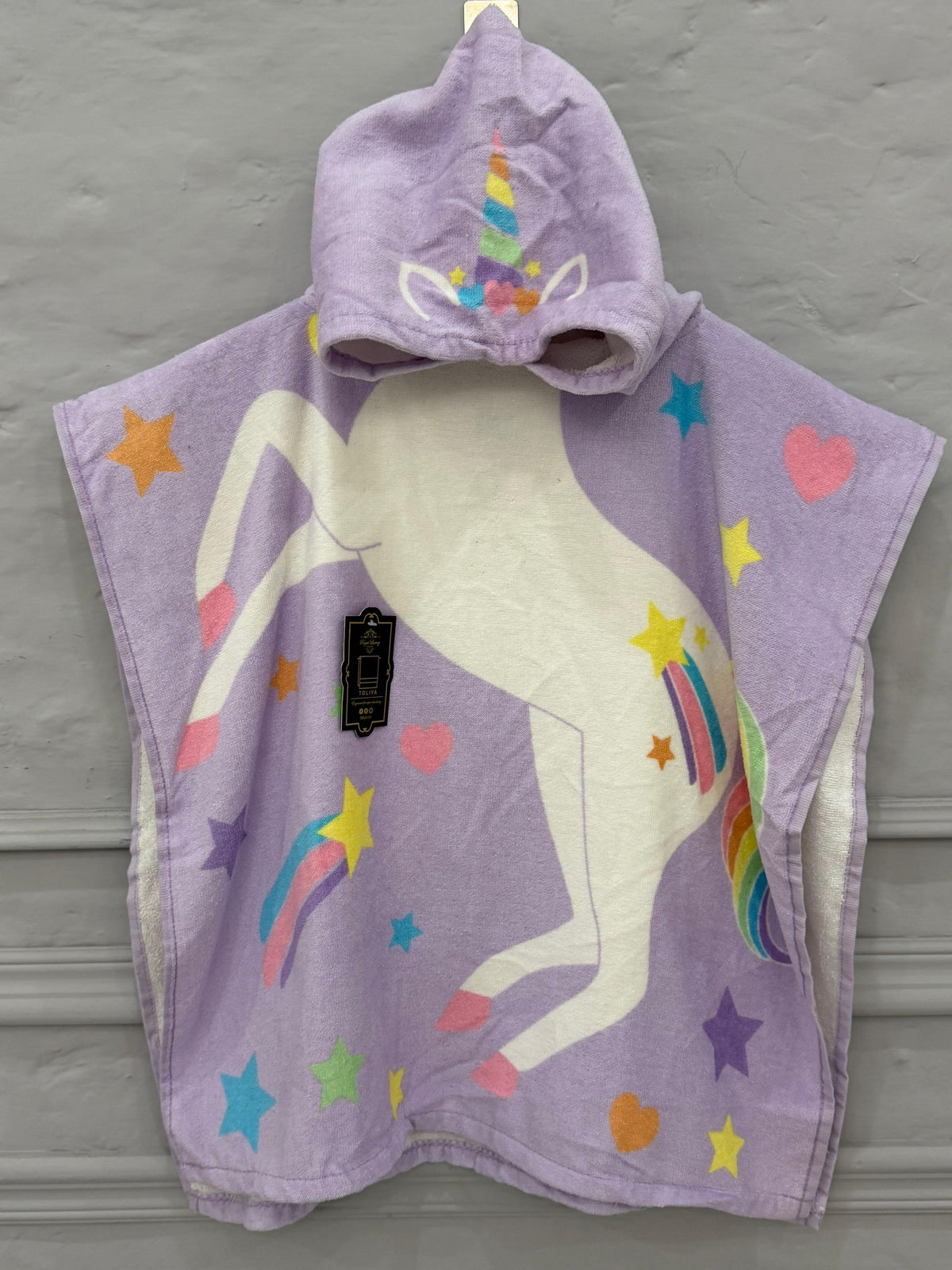 Purple unicorn hooded towel with colorful designs on a gray background