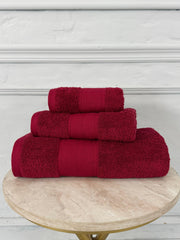 Set of red towels on a wooden table with a white decorative wall in the background