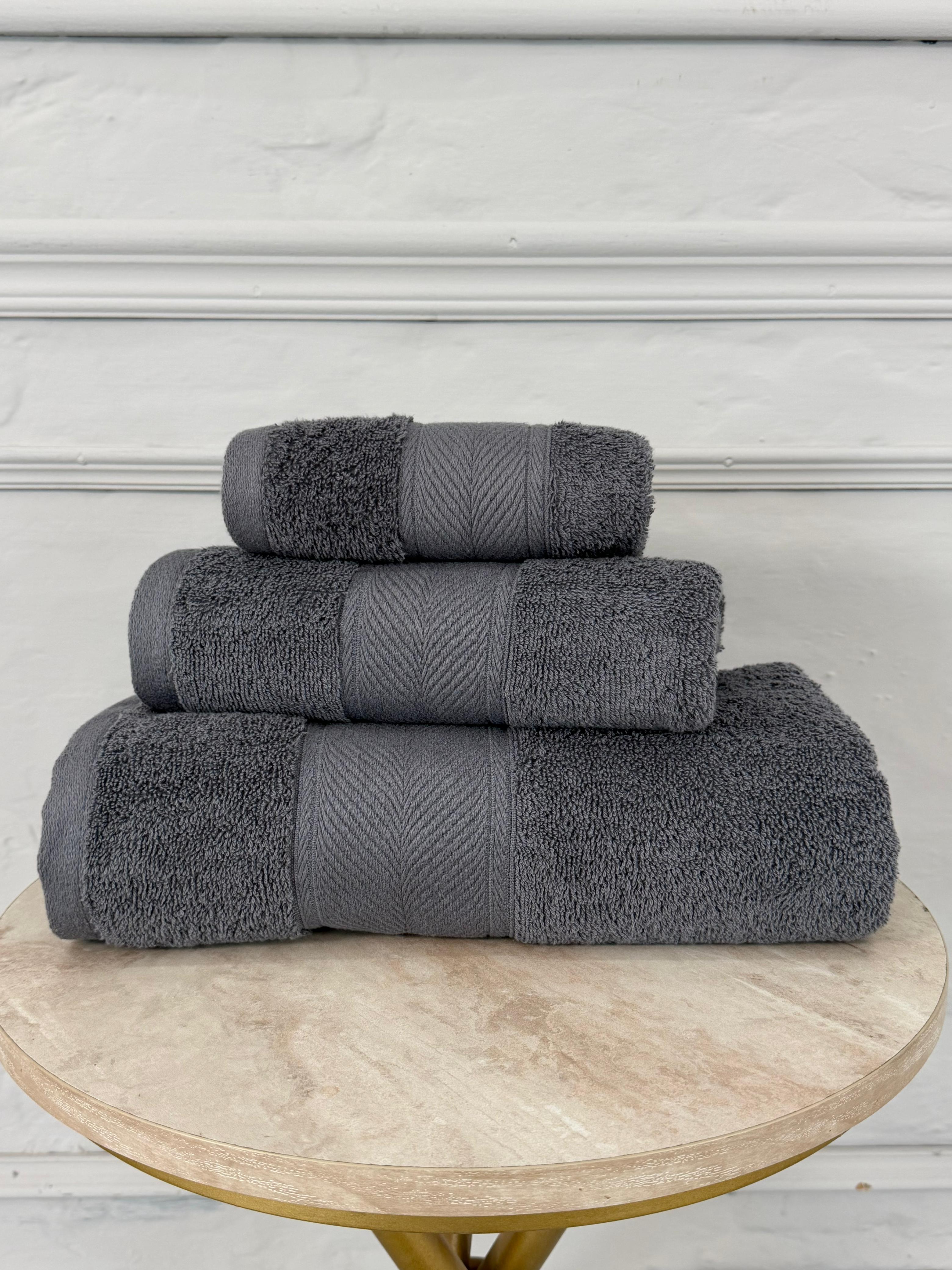 Stack of gray towels on a wooden table with a white wall background