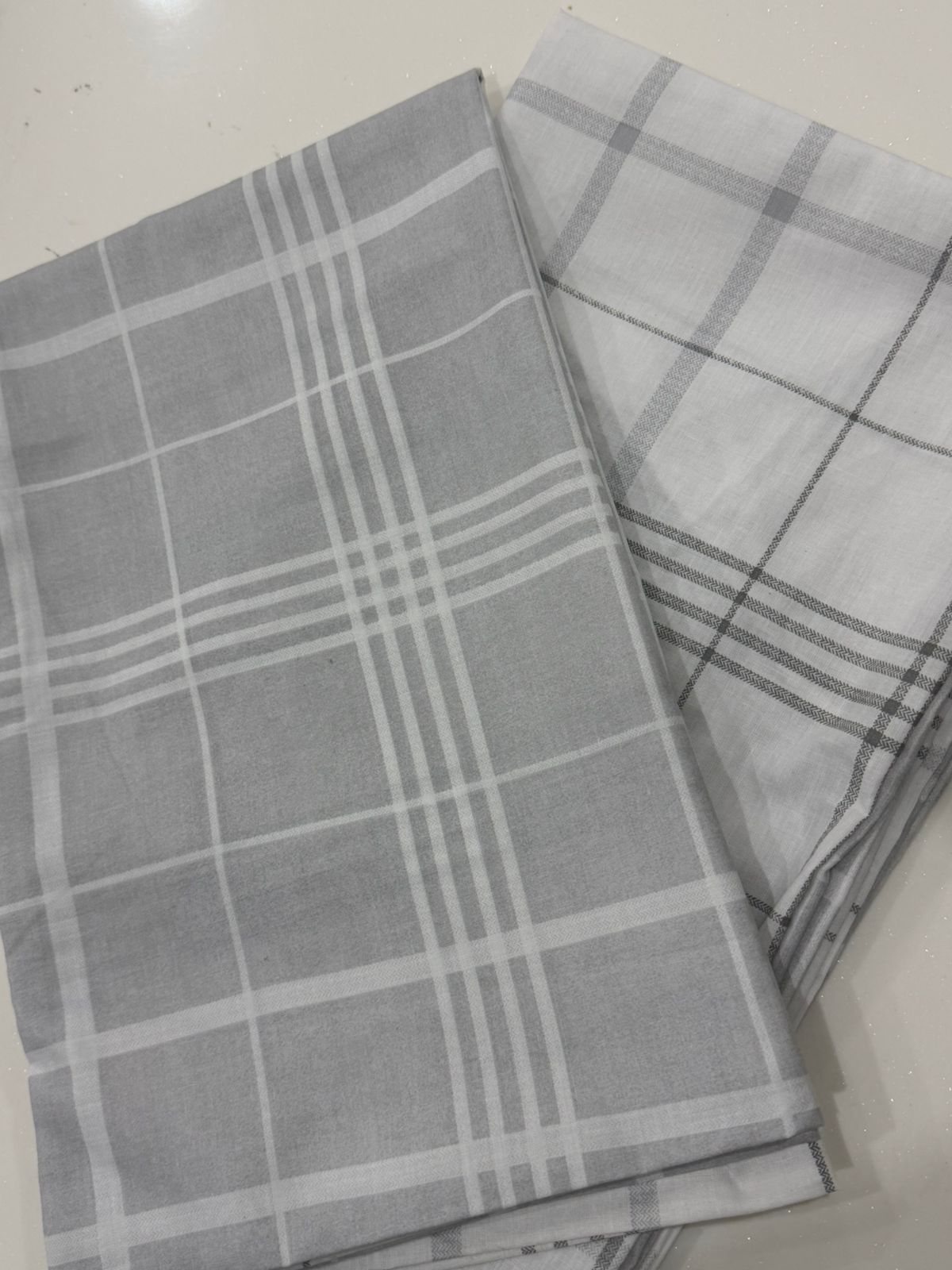 Two gray checkered towels on a white surface
