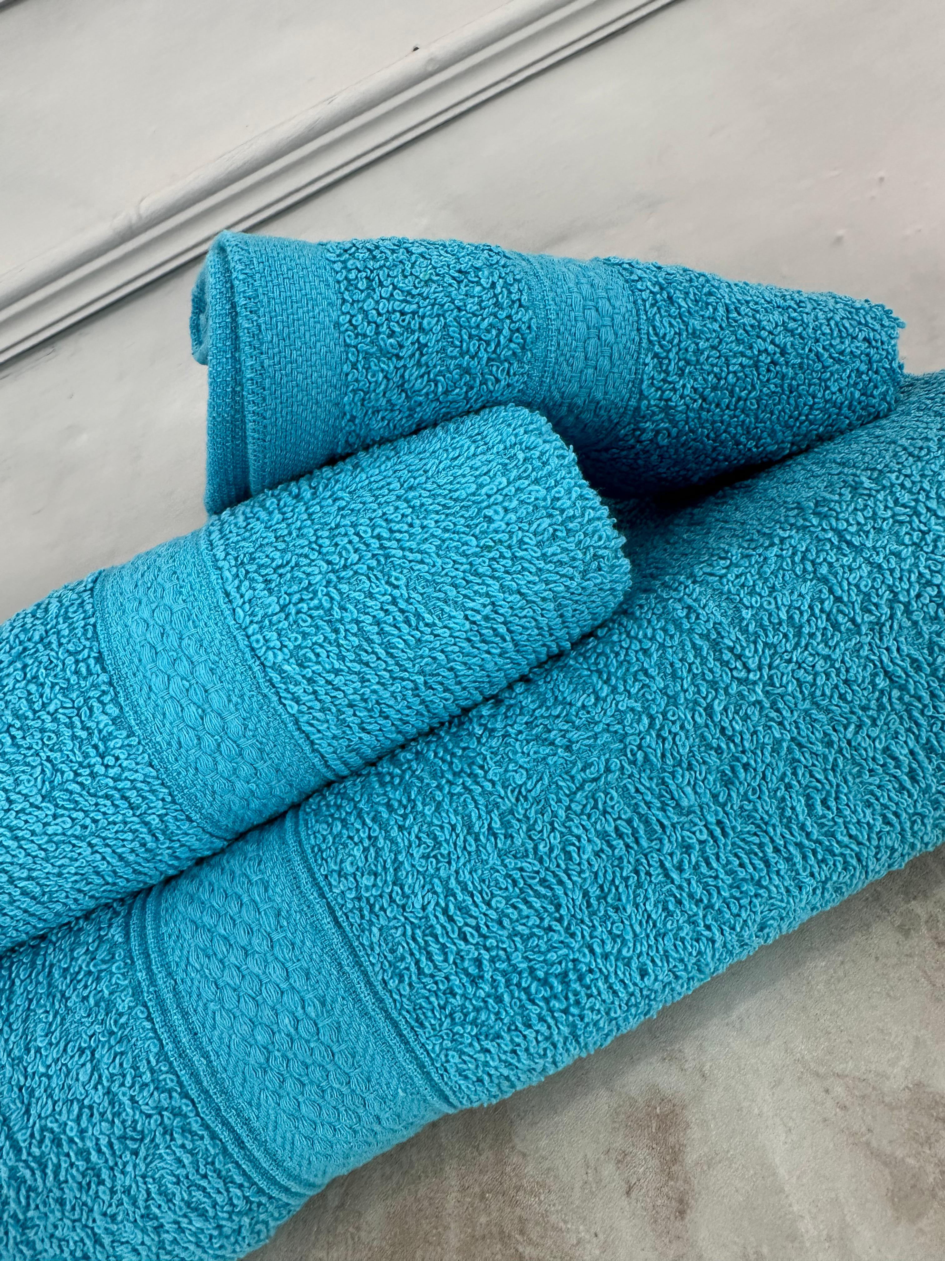 Three blue towels stacked on a concrete surface