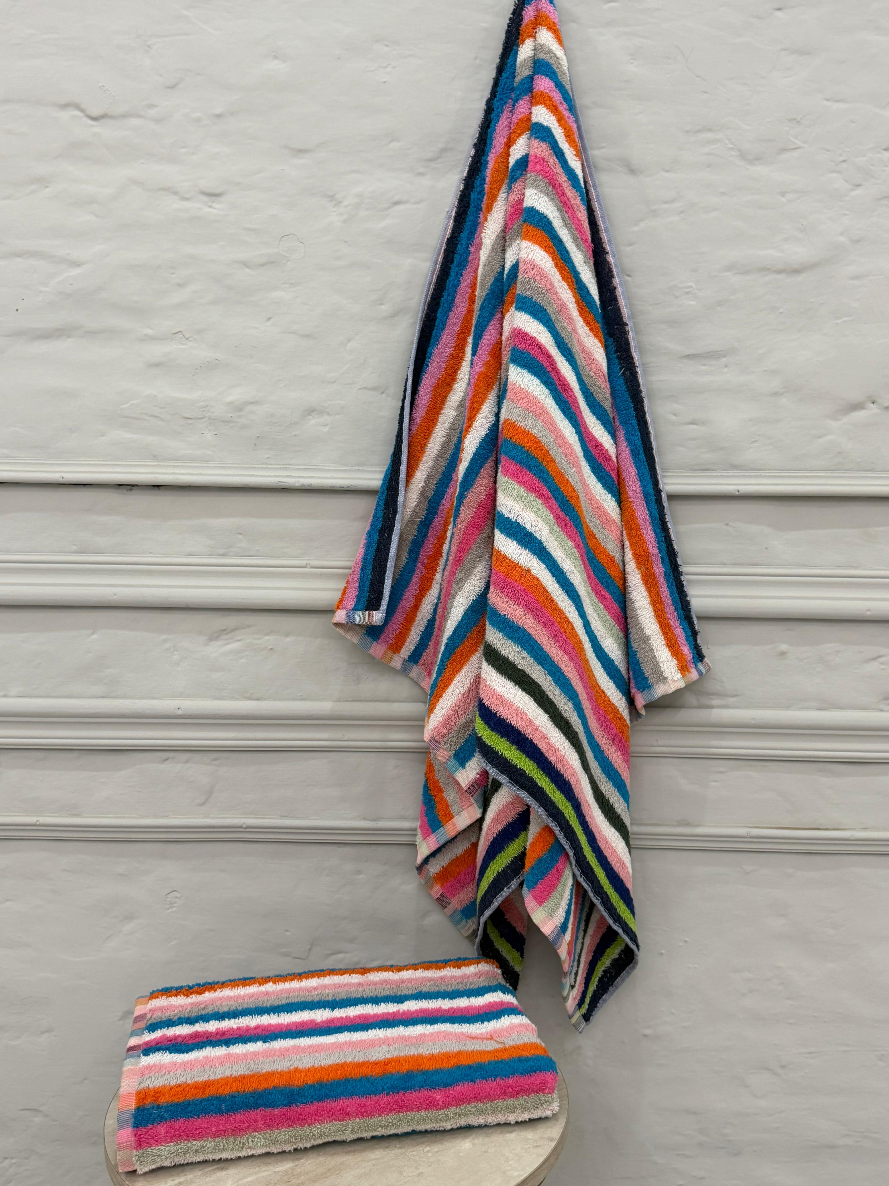 Colorful striped towel and washcloth on a wooden surface