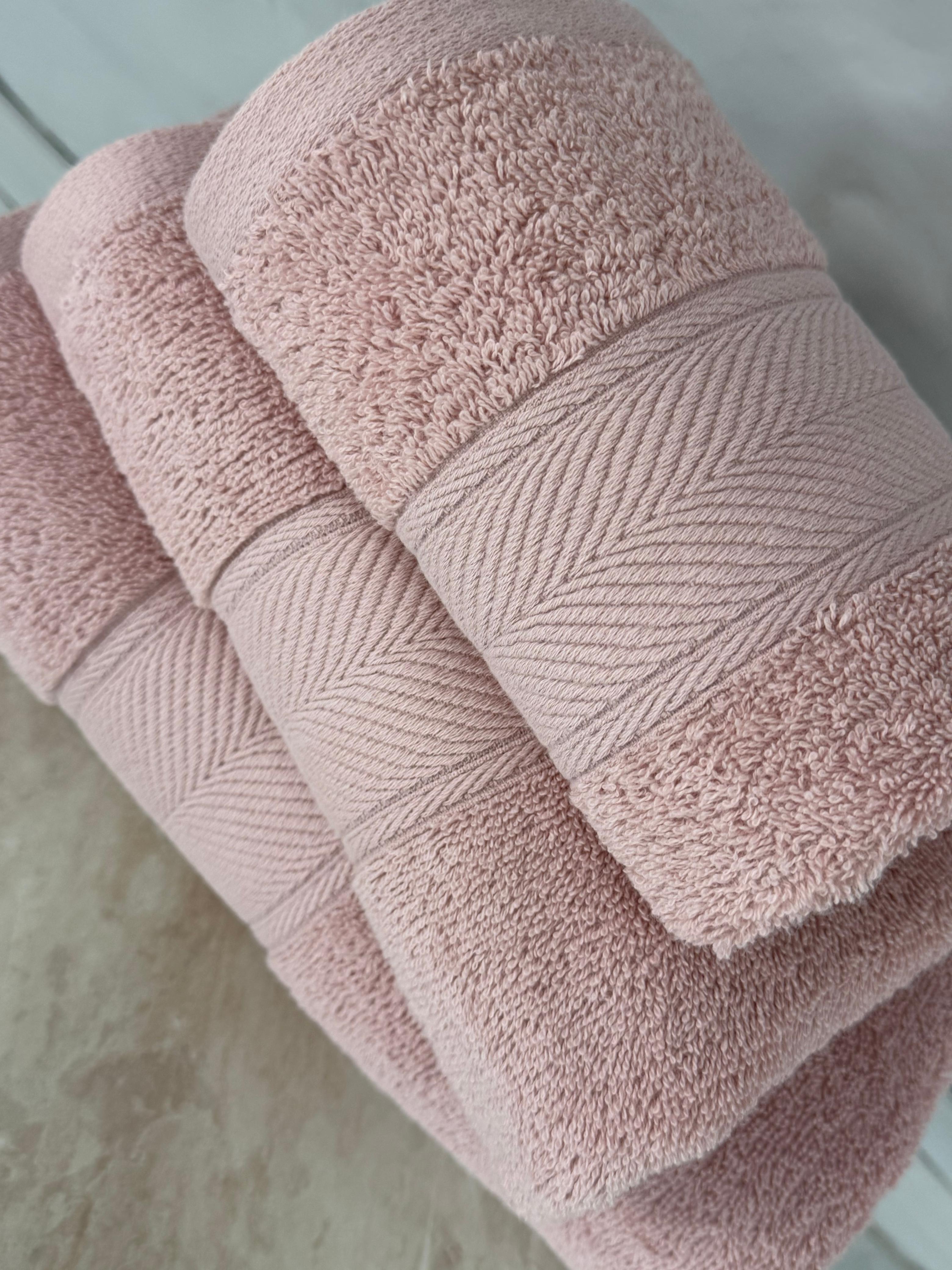 Stack of pink towels on a light wooden surface