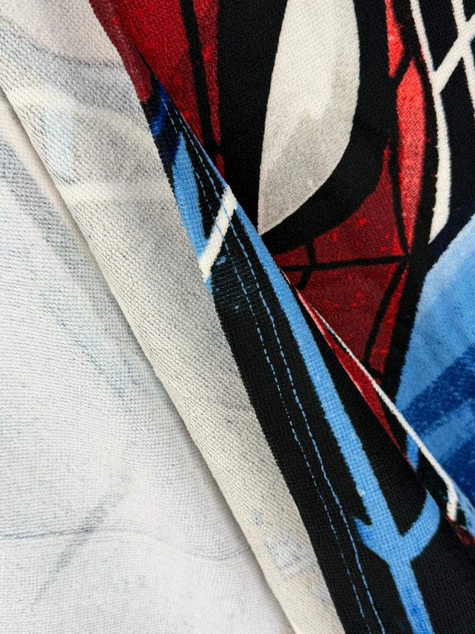 Close-up of a fabric with abstract pattern in red, blue, and black on a textured surface.