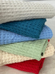 Stack of textured towels in various colors on a neutral background