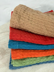Stack of folded textured towels in various colors on a light background