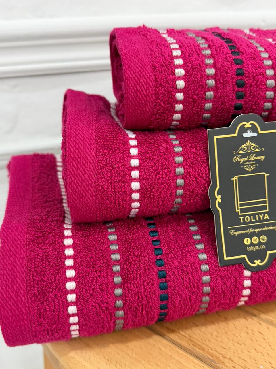 Stack of pink towels with a visible brand tag on a wooden surface.
