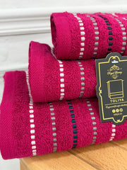 Stack of pink towels with a visible brand tag on a wooden surface.