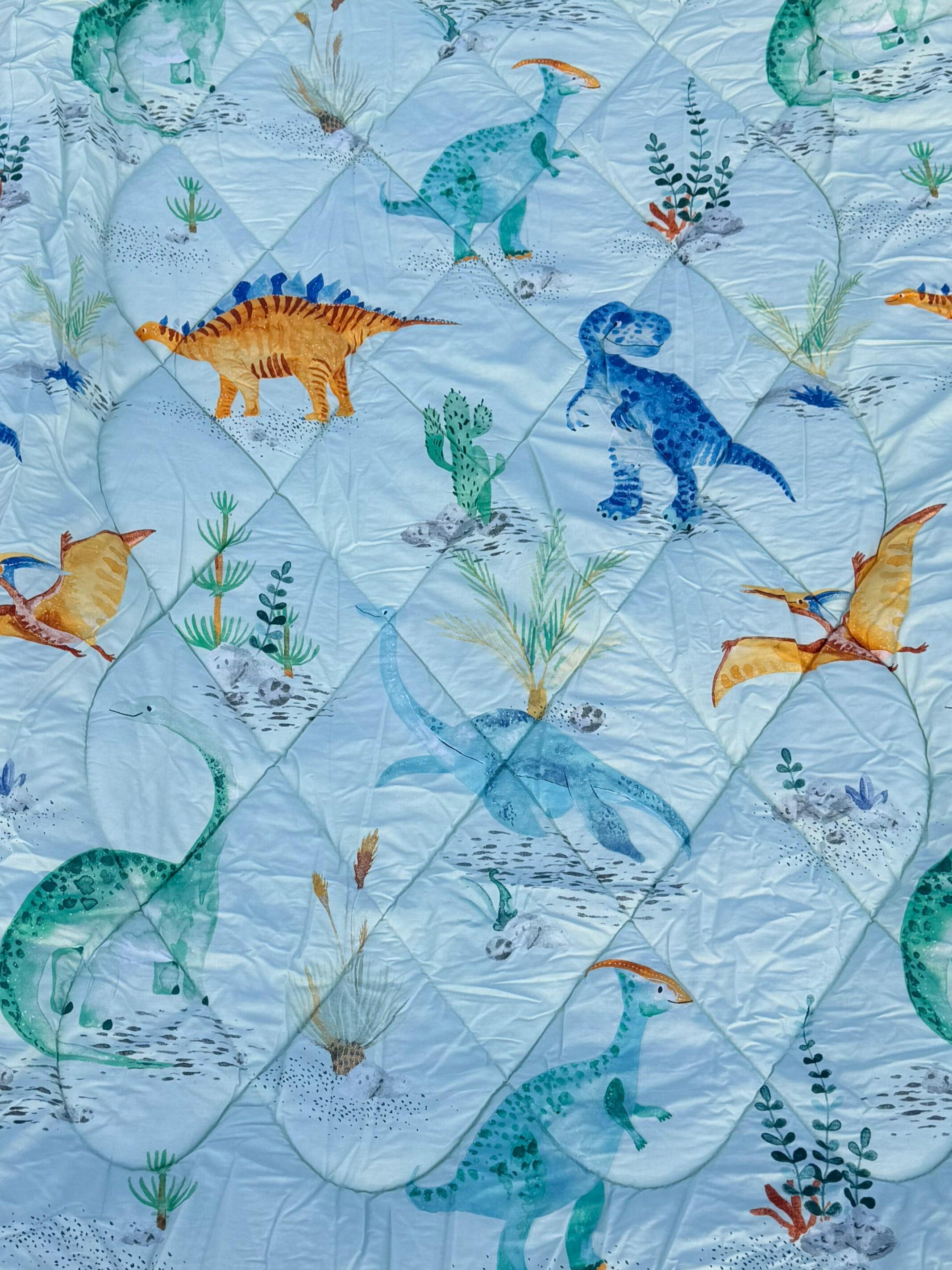 Quilt with colorful dinosaur pattern on a blue background