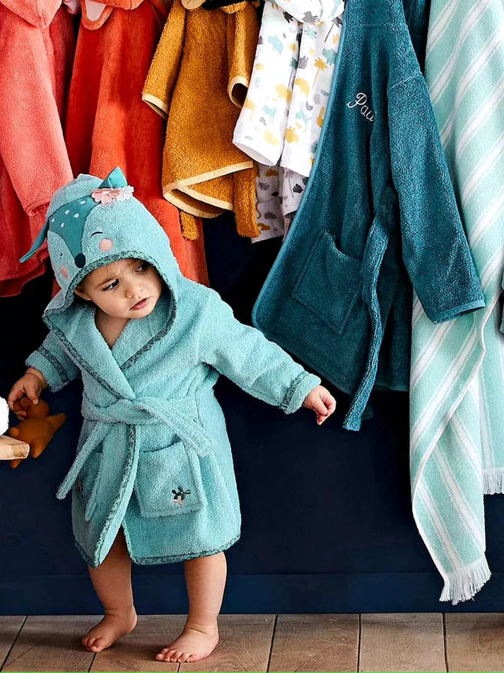 Child wearing a teal hooded robe with a cartoon character on a white background