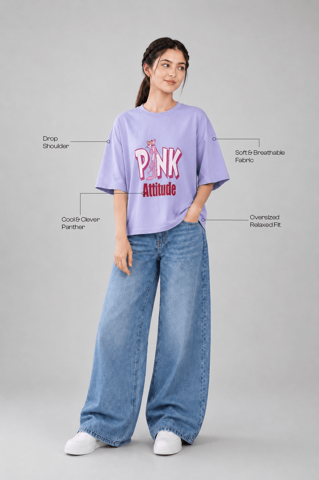 A woman modeling a light purple t-shirt with 'PINK Attitude' printed on the front, paired with wide-leg blue jeans and white sneakers, set against a plain gray background with text callouts highlighting the garment's features.